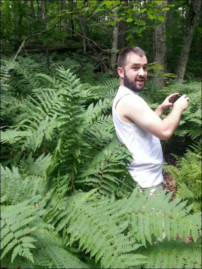 Philip Crim standing among ferns in a woodland.