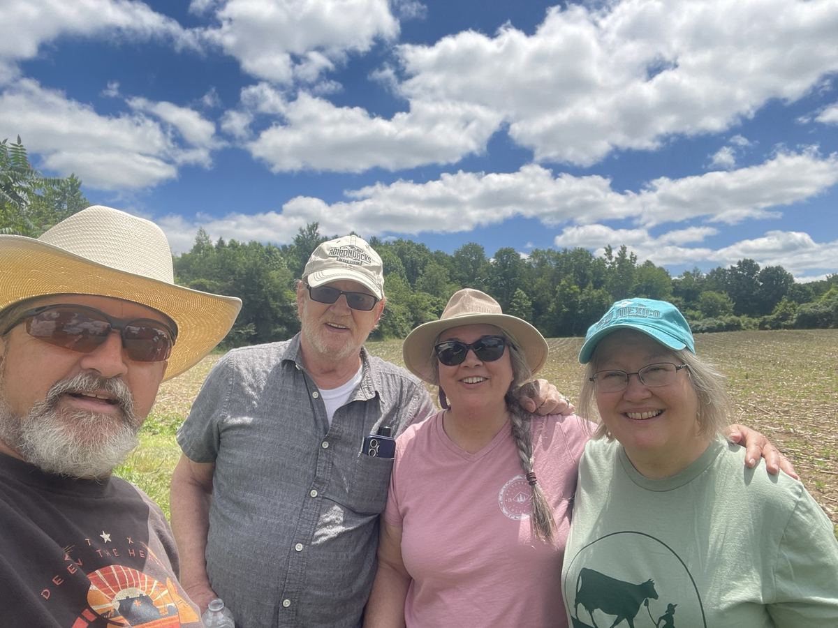 Four smiling visitors standing together in a field at Limeledge.